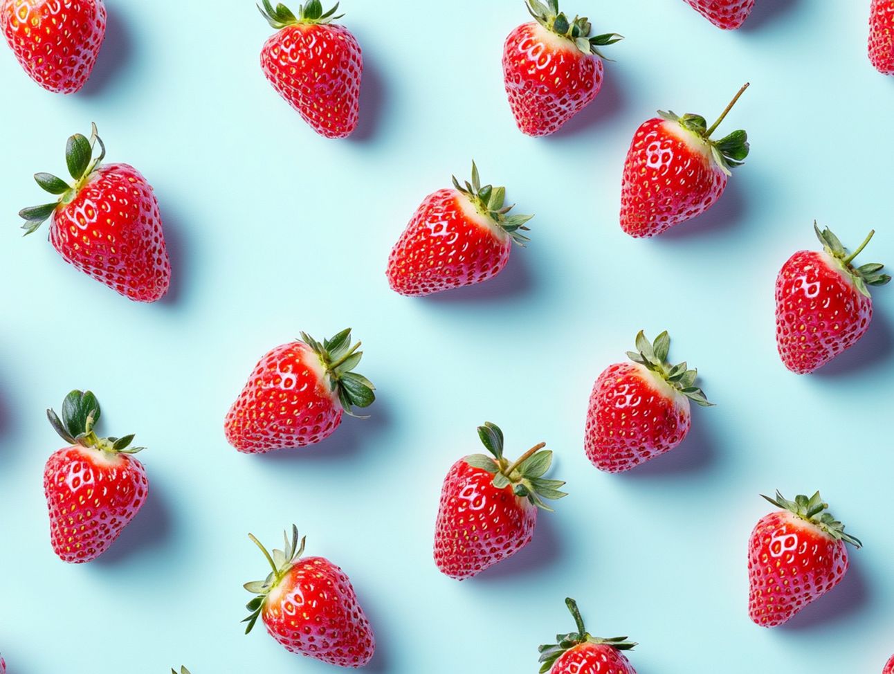 minimalist image with a pastel blue background, featuring several ripe red strawberries scattered randomly across the surface. The strawberries should be placed in an organic pattern with varying distances between them, and one green strawberry stem should be included among the berries. Use soft lighting to create gentle shadows under the strawberries, adding depth to the composition. The overall visual should be appealing, highlighting the vibrant color contrast between the strawberries and the pink background. Some strawberries can be smashed.